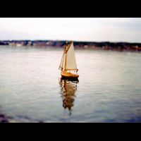 a small sailboat is floating on top of a body of water .