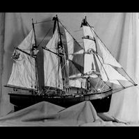 a black and white photo of a model sailboat on a table .