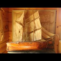 a wooden model of a sailboat is hanging on a wall .