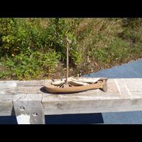 a small wooden boat is sitting on a wooden railing next to a body of water .