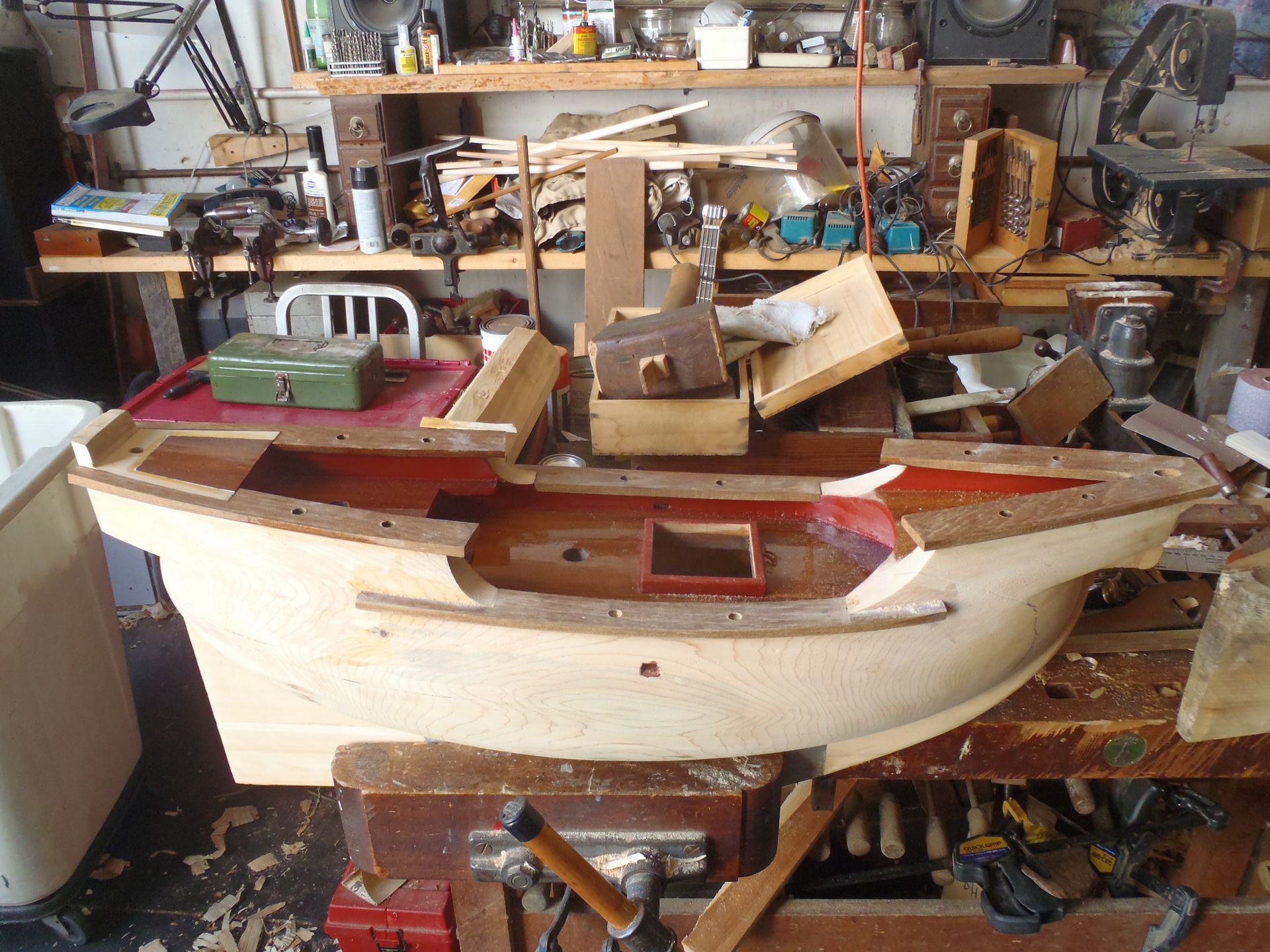 a wooden boat is sitting on a workbench in a workshop