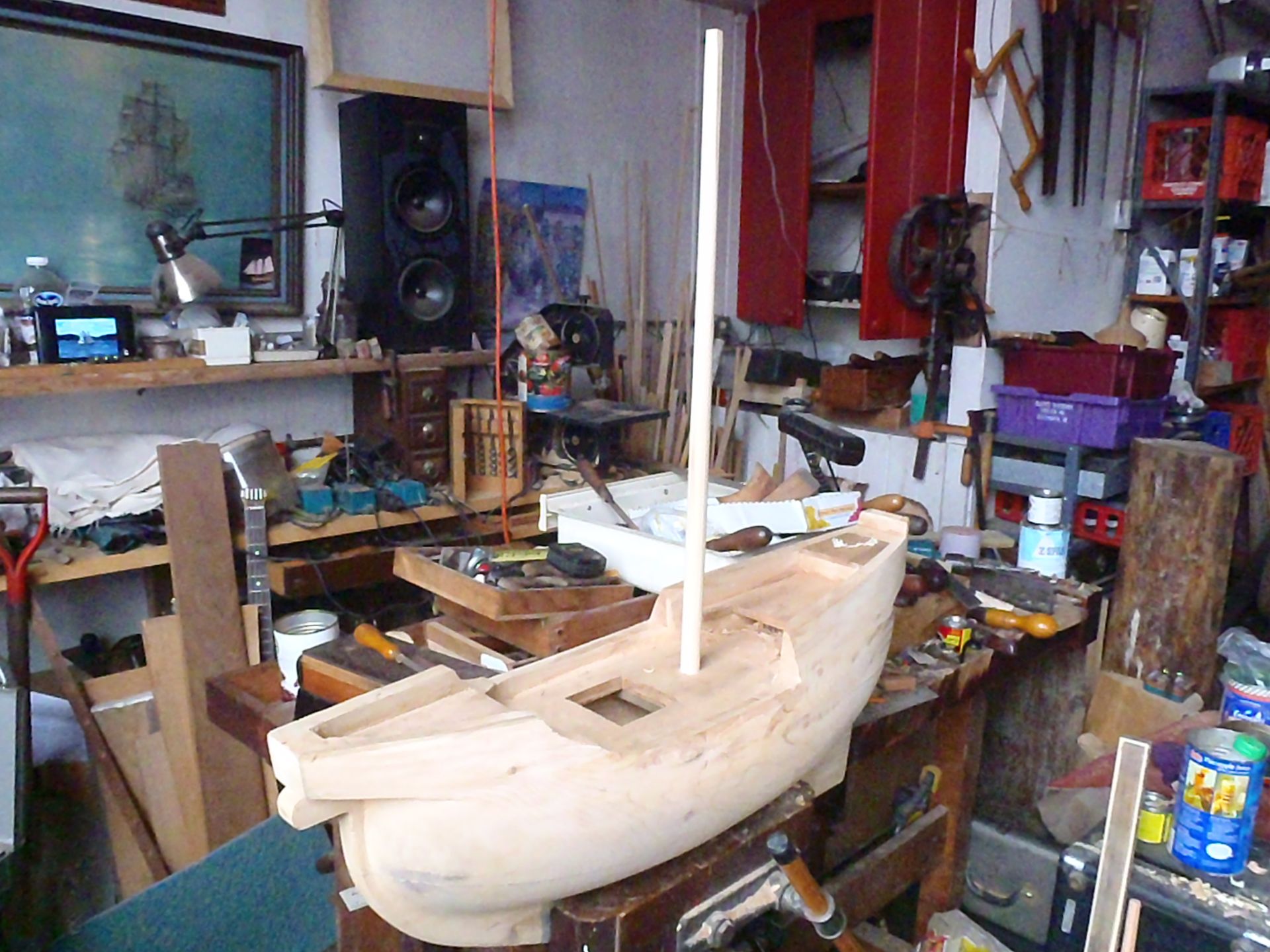 a wooden boat is being built in a messy workshop