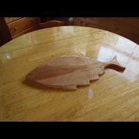 a wooden cutting board in the shape of a fish is sitting on a wooden table .