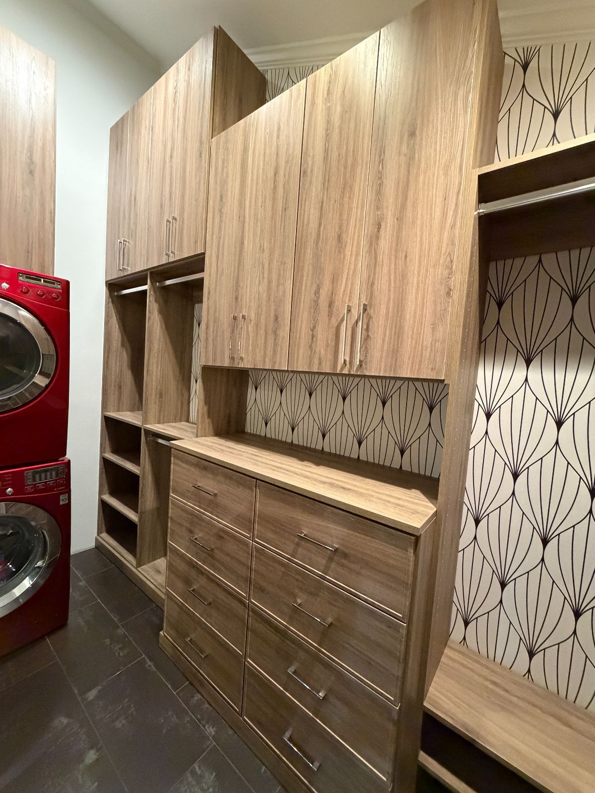 Custom wooden closet with drawers, shelves, and cabinets; a red washer and dryer are visible on the left.