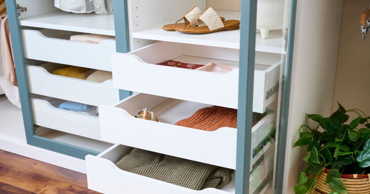 a closet with drawers and shelves filled with clothes and shoes .