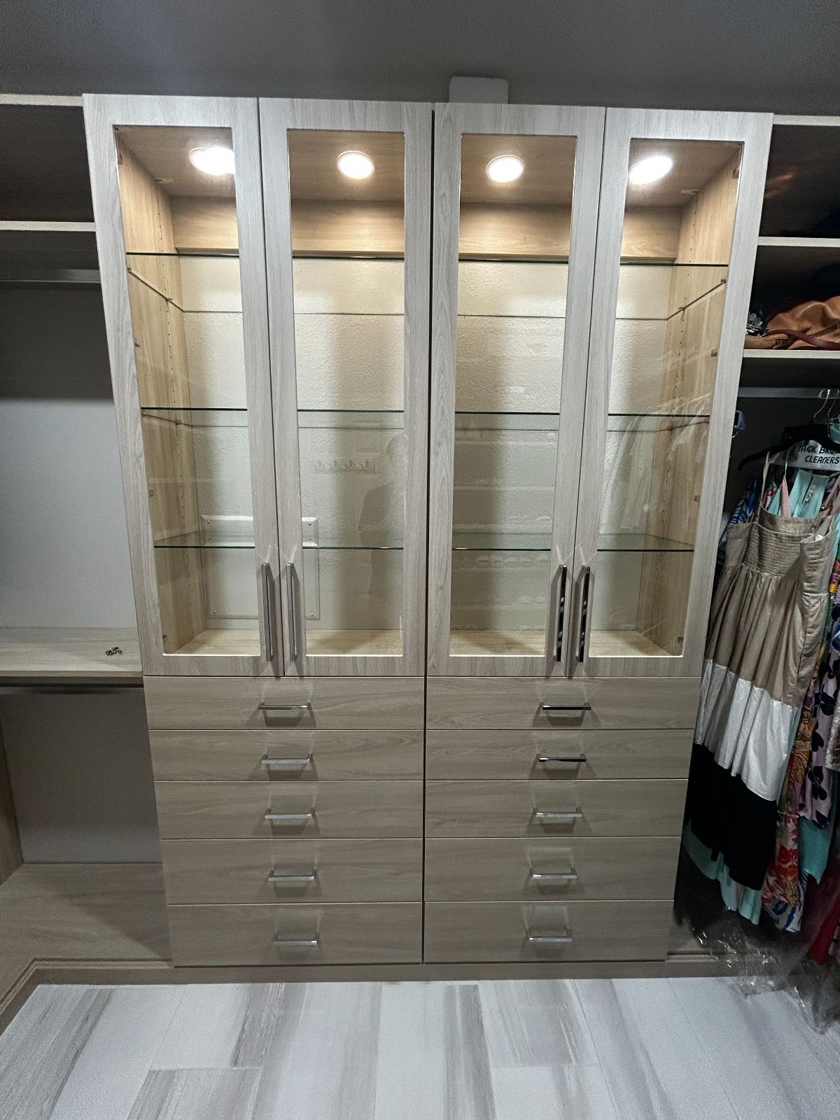 Closet with light wood cabinets, glass door display, and drawers.