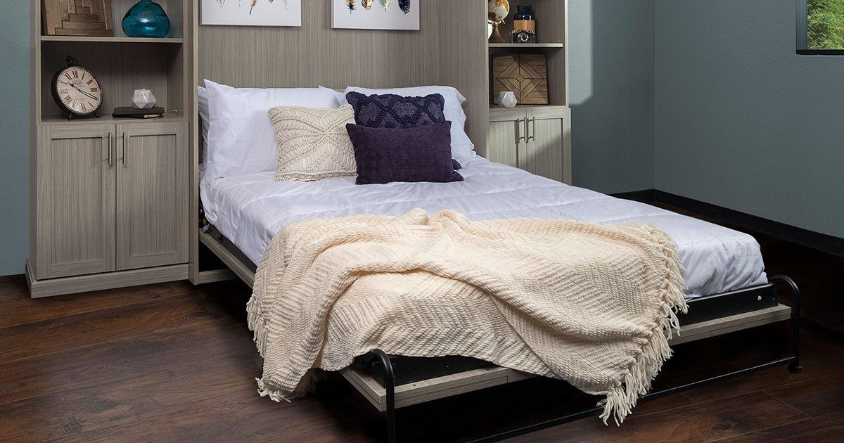 a murphy bed with a blanket on it in a spare room .
