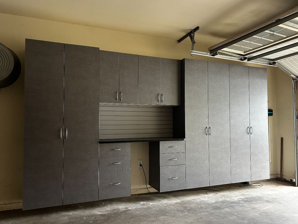Gray garage storage cabinets with a workspace against a light yellow wall.