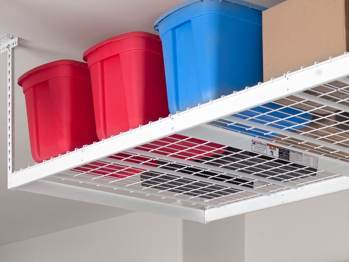 a shelf in a garage with red and blue bins and boxes on it .