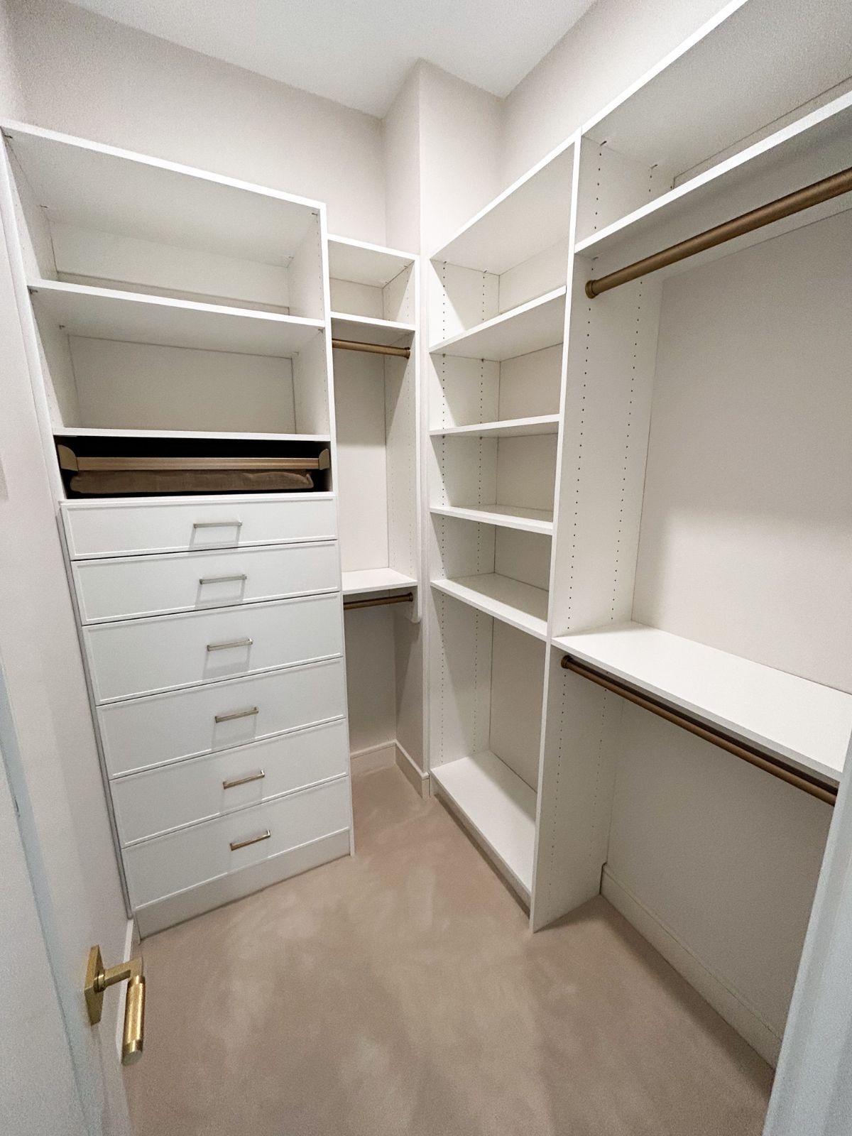 A walk in closet with lots of shelves and drawers.