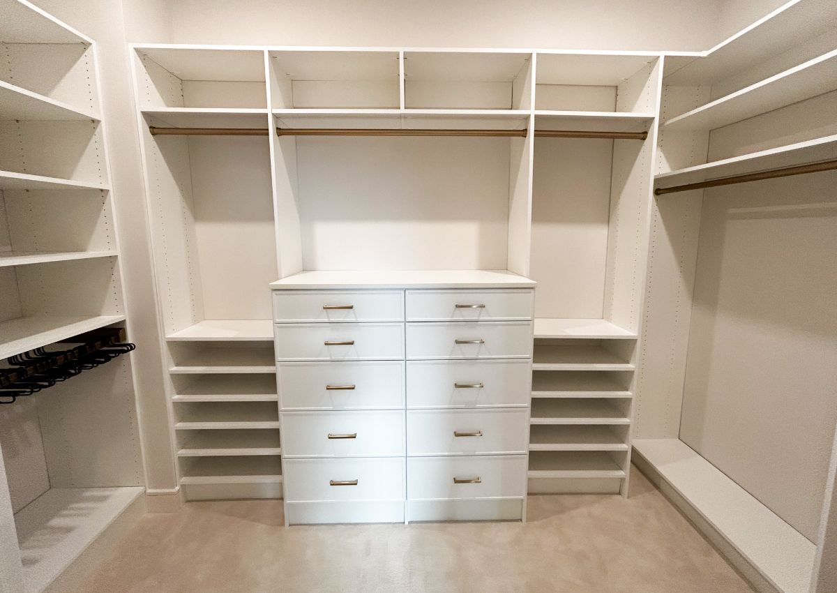 A walk in closet with lots of shelves and drawers.