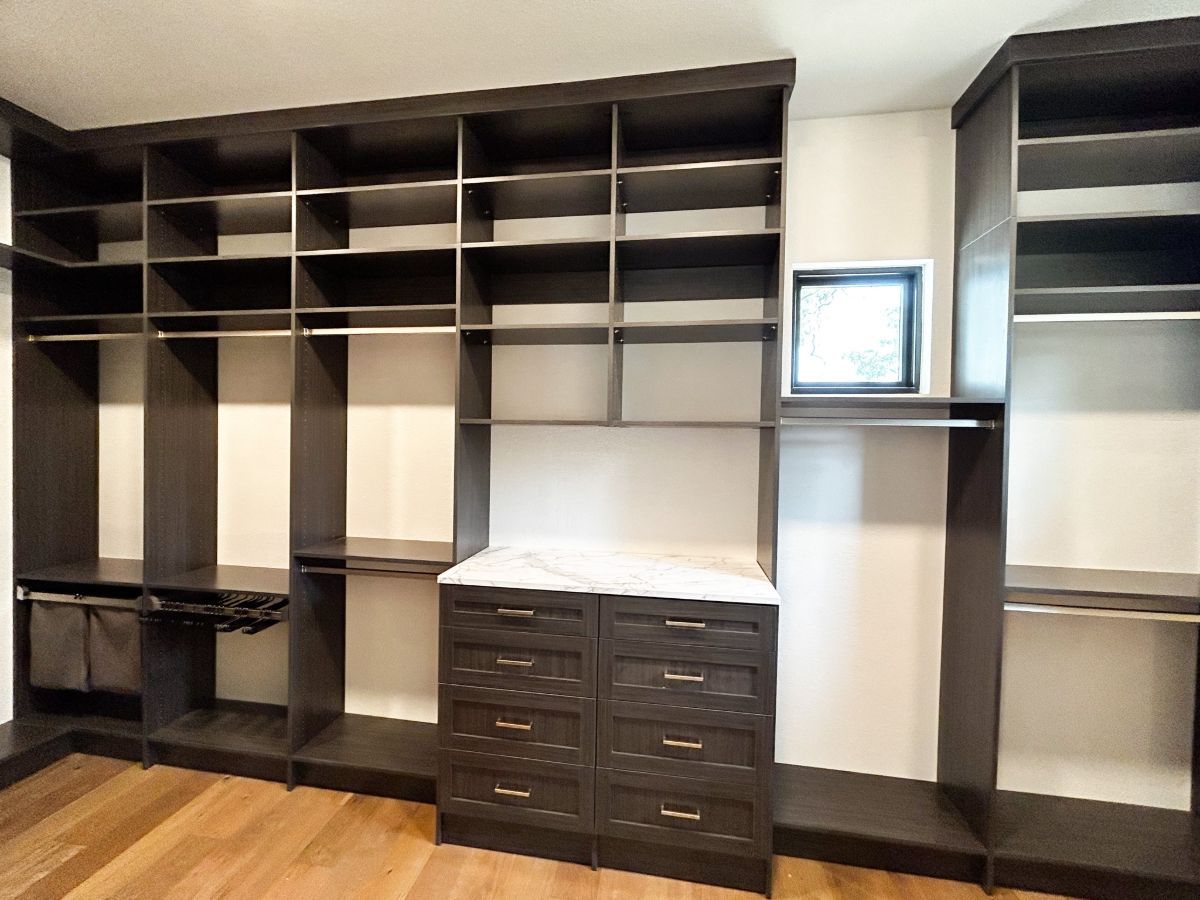 A walk in closet with lots of shelves and drawers