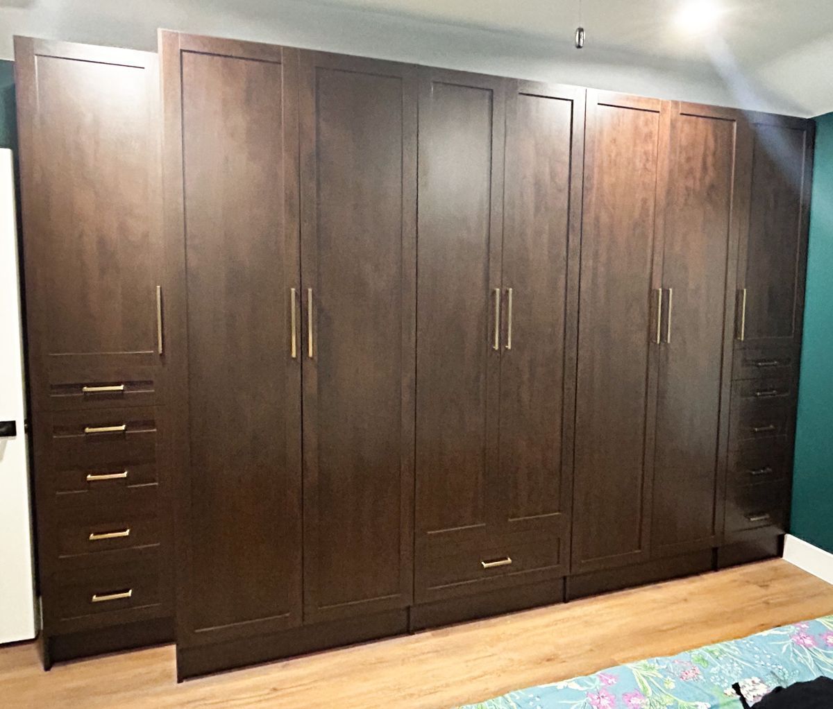 A bedroom with a lot of wooden cabinets and drawers.