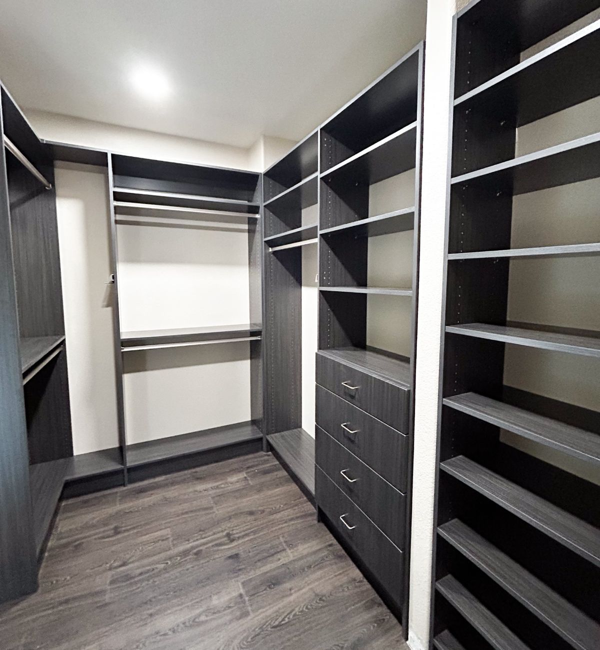 A walk in closet with lots of shelves and drawers