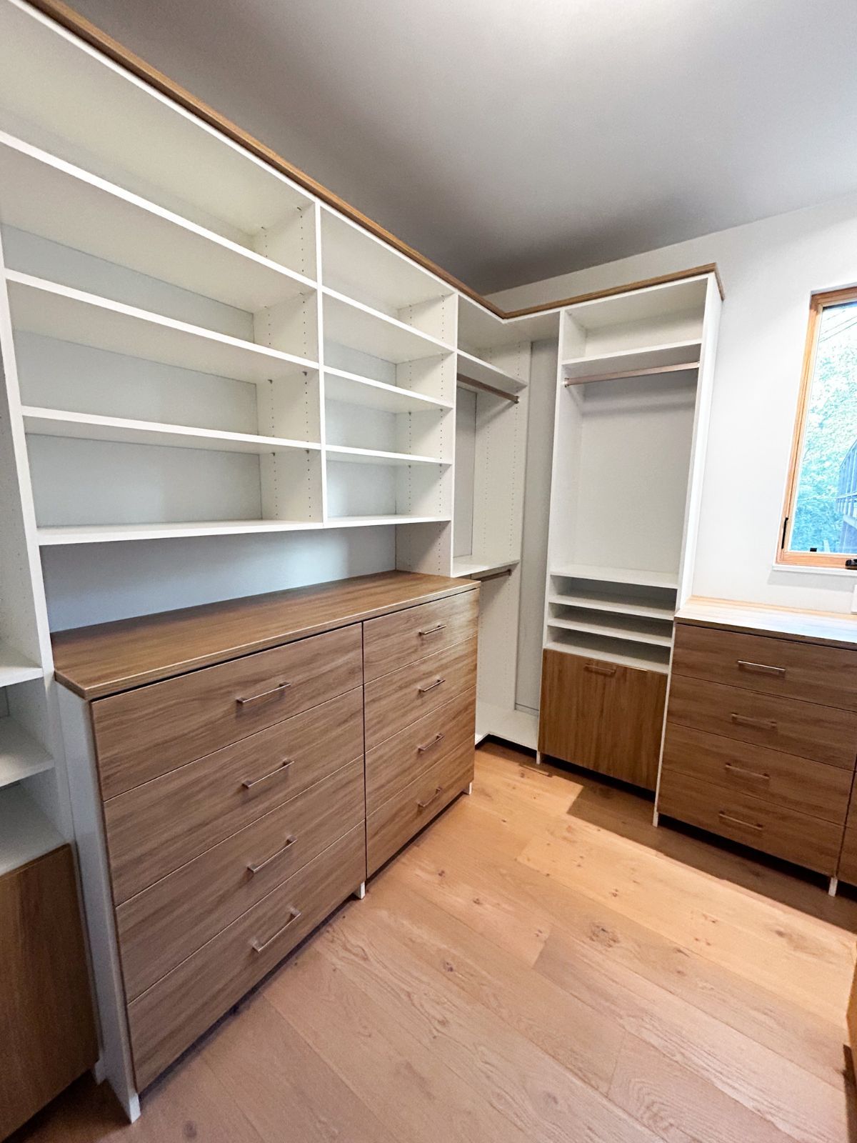 A walk in closet with lots of shelves and drawers.