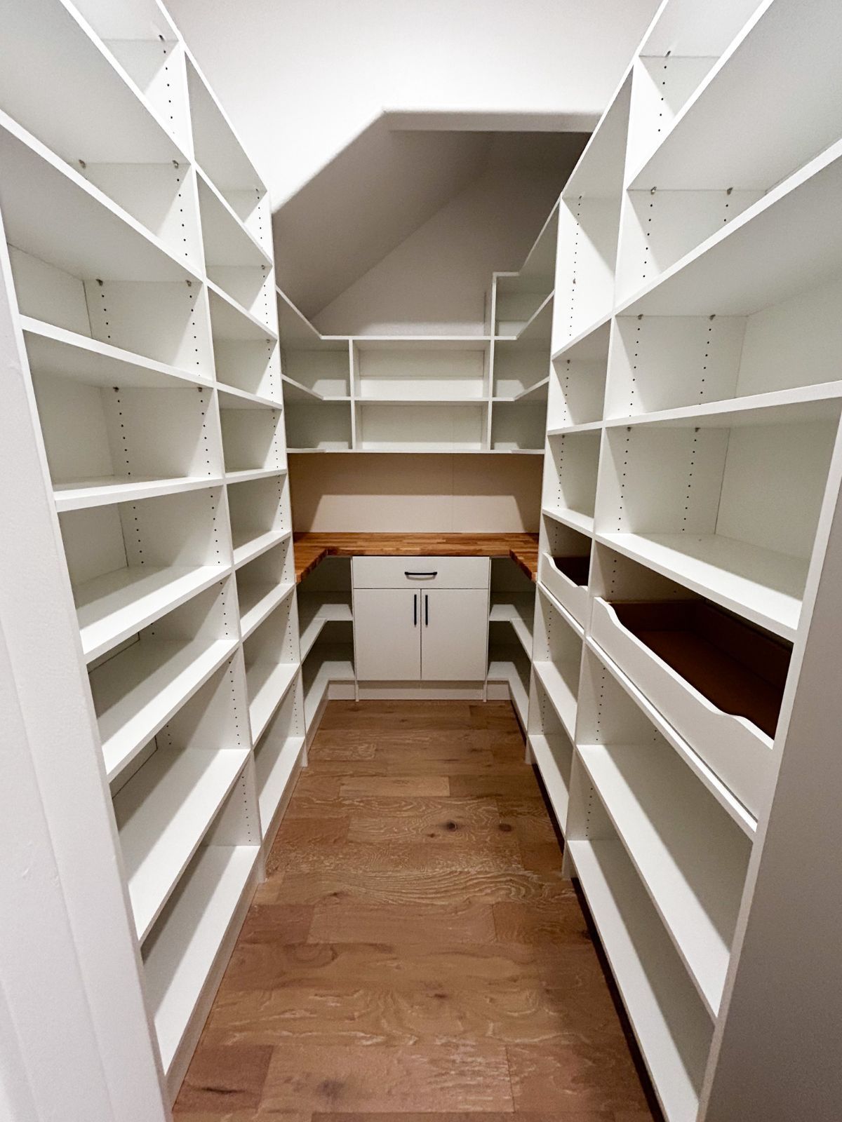 A walk in closet with lots of shelves and a desk.