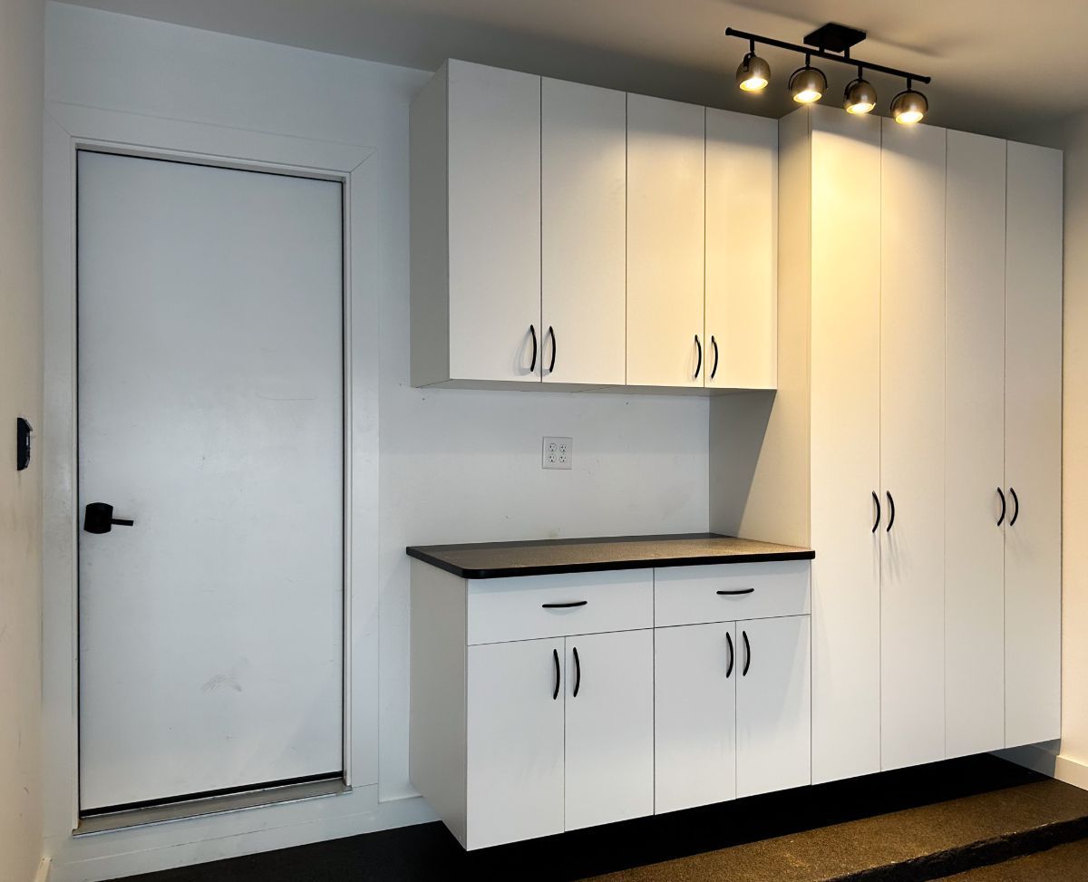 A kitchen with white cabinets and a white door