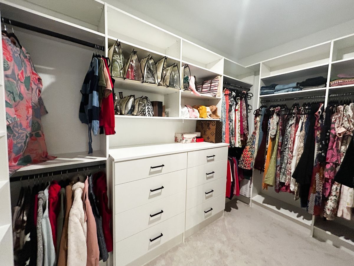 A walk in closet filled with lots of clothes and shoes.