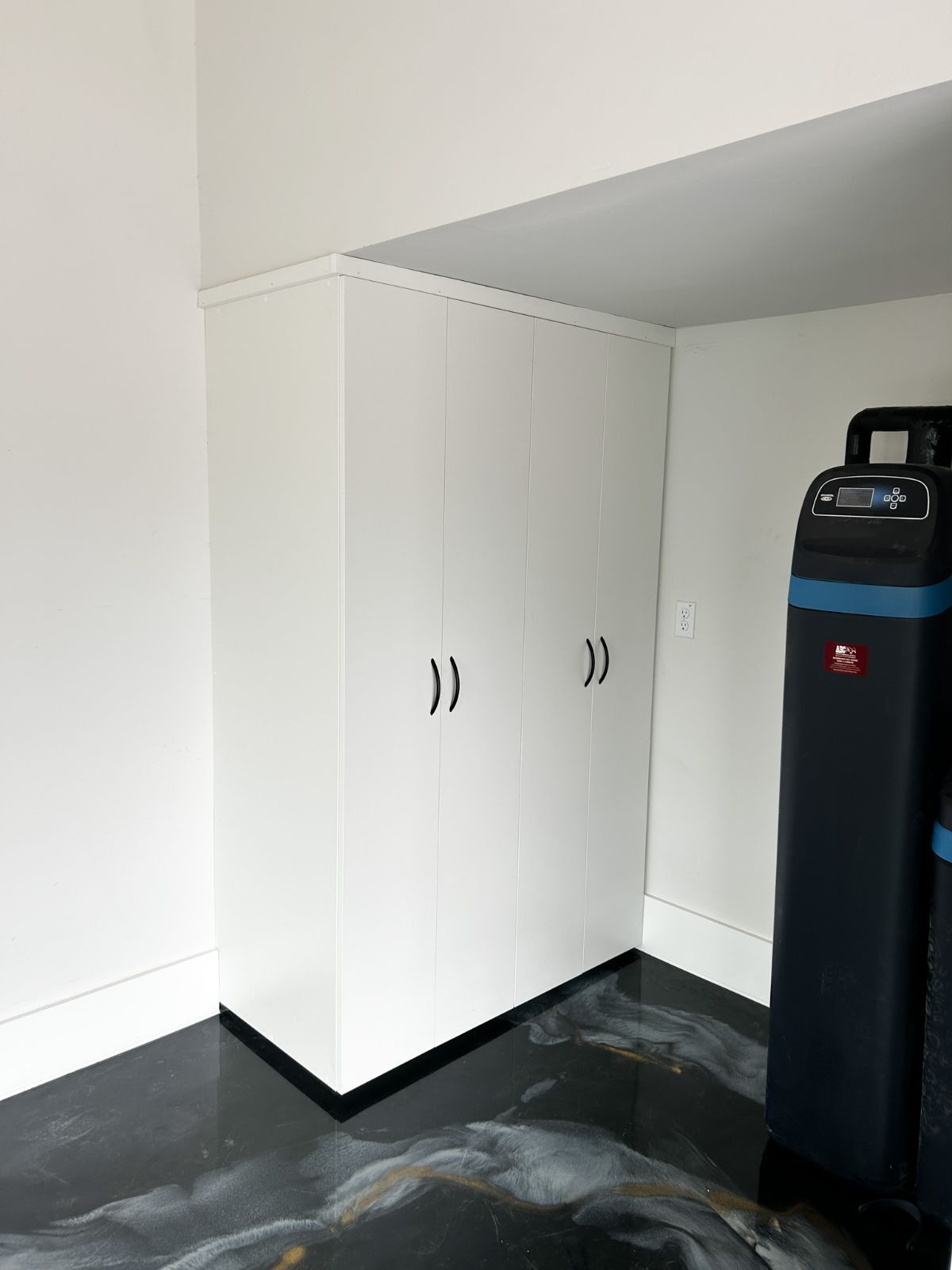 There is a water softener in the corner of the room.