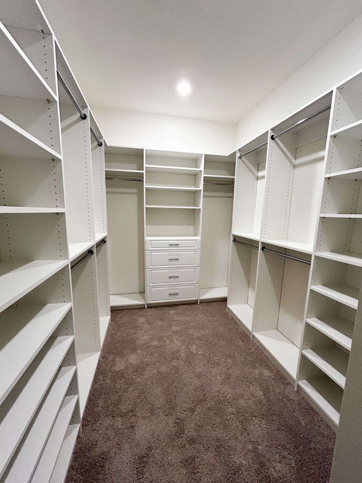 A large walk in closet with lots of shelves and drawers.