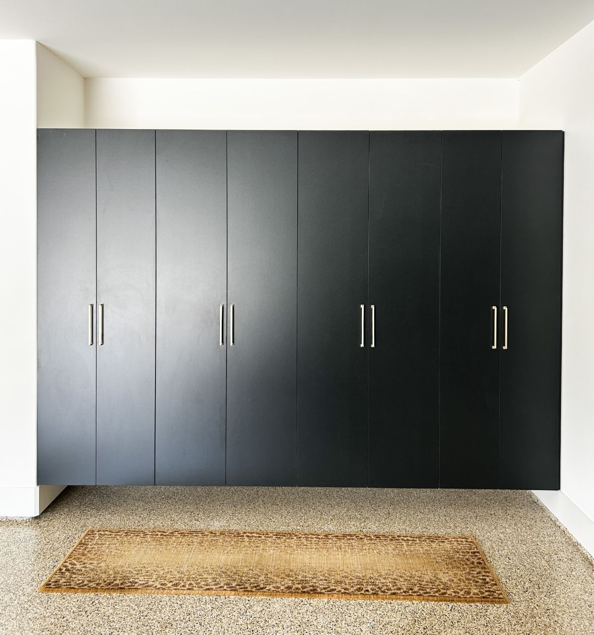 A garage room with black cabinets and a rug on the floor