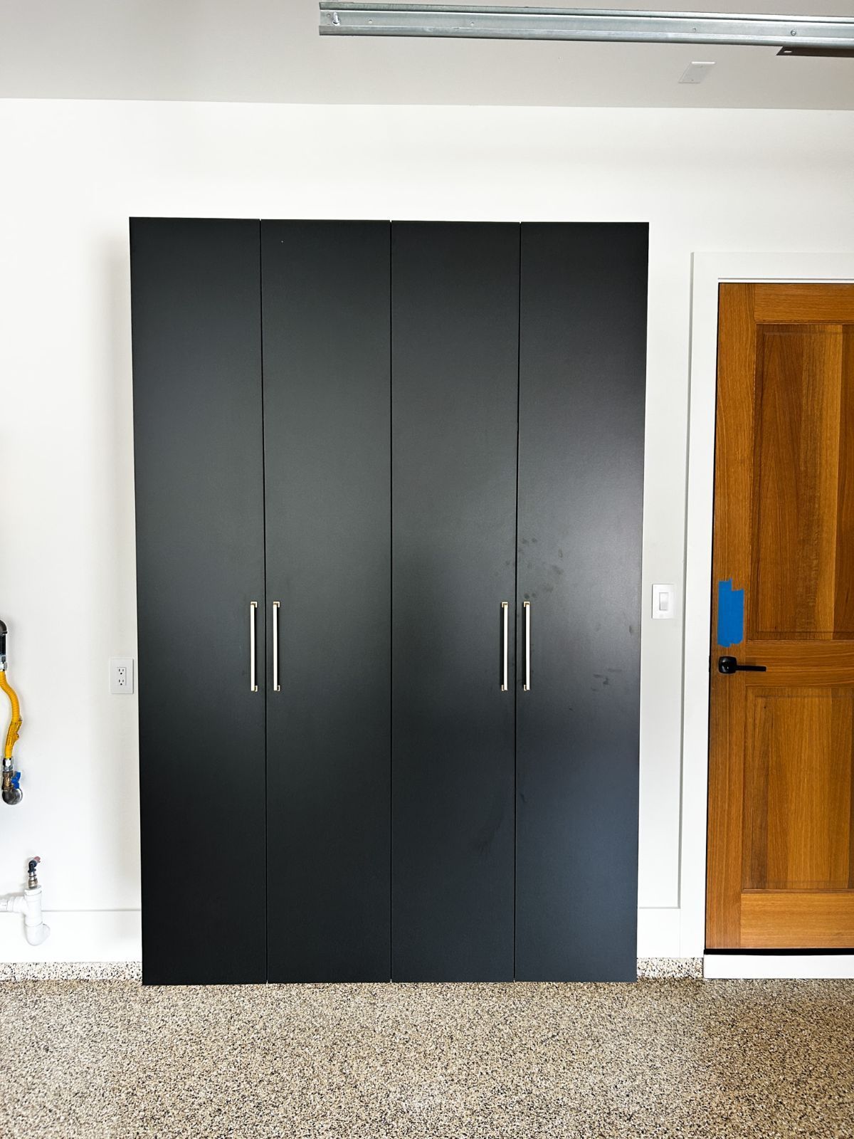 A garage with black cabinets and a wooden door.