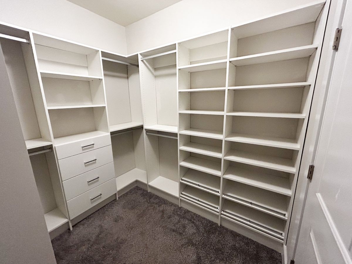 A walk in closet with lots of shelves and drawers.
