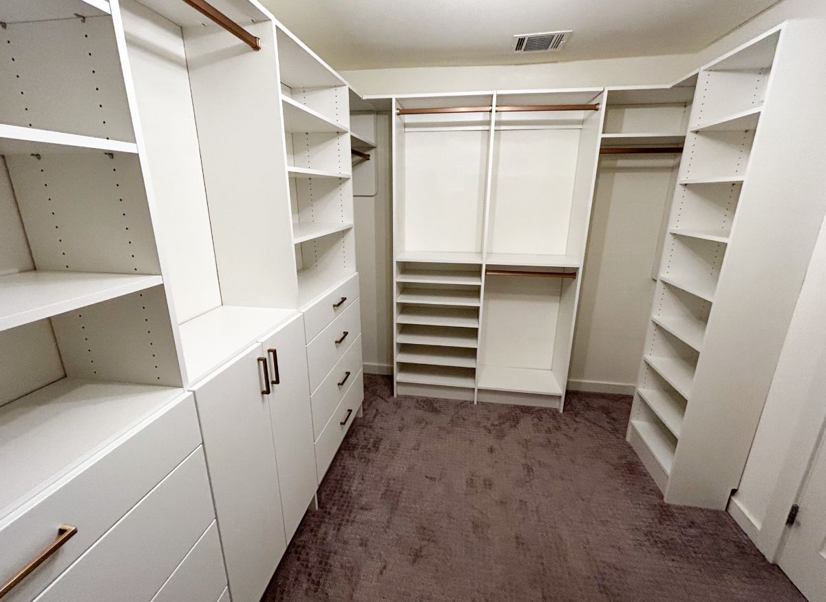 A large walk in closet with lots of shelves and drawers.