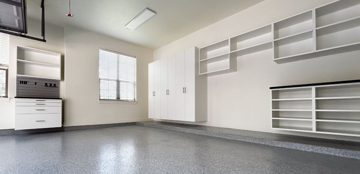 A large empty garage with lots of shelves and cabinets.