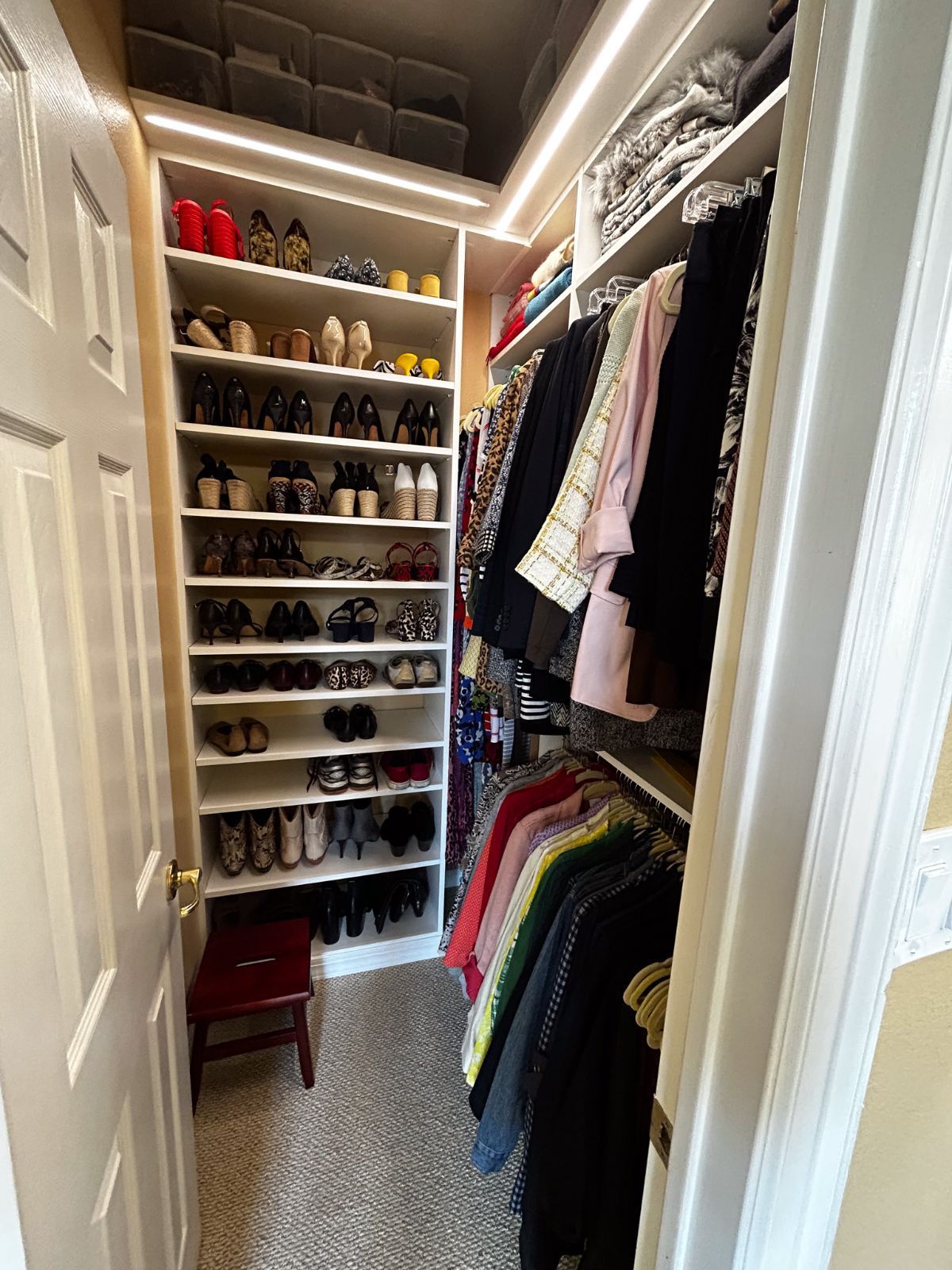 A walk in closet filled with lots of clothes and shoes.