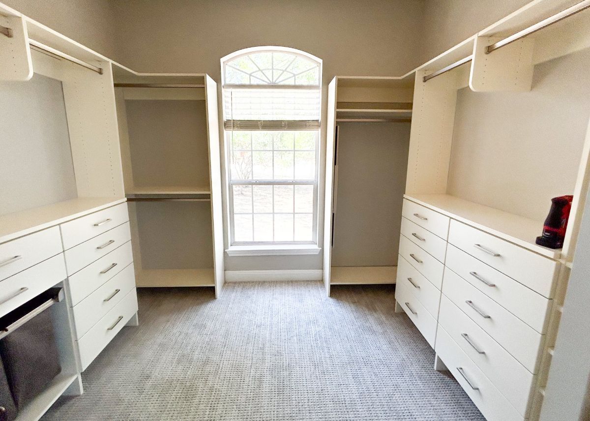 A walk in closet with lots of drawers and a window.