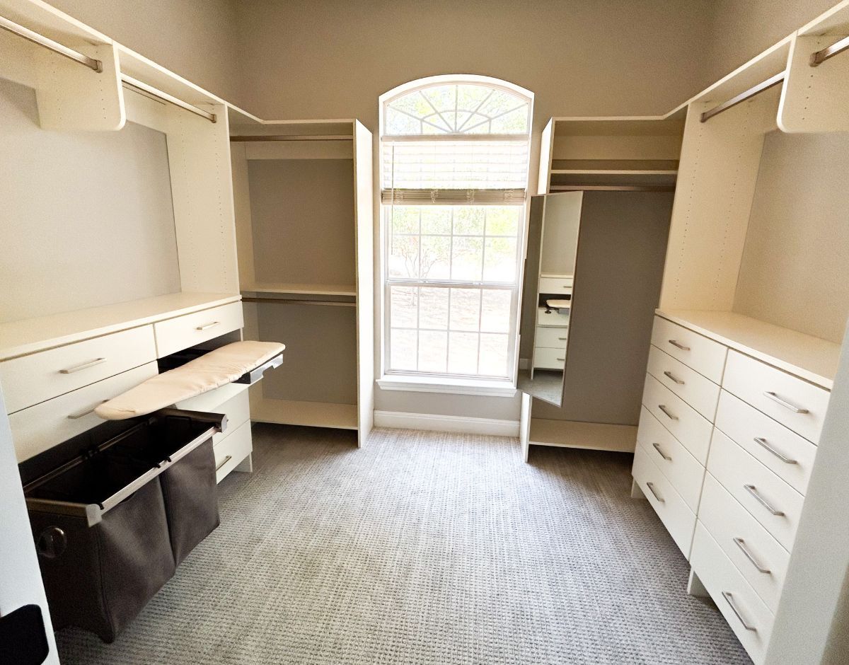 A walk in closet with lots of shelves and drawers and a window.