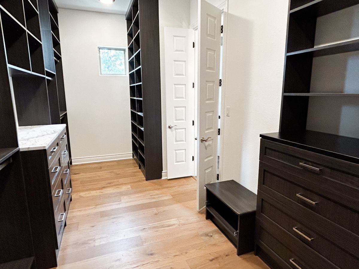 A walk in closet with lots of shelves and drawers.