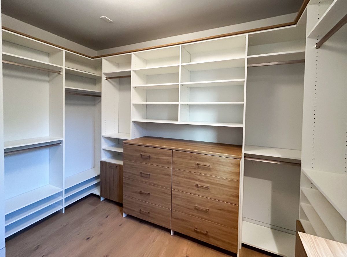 A walk in closet with lots of shelves and drawers.