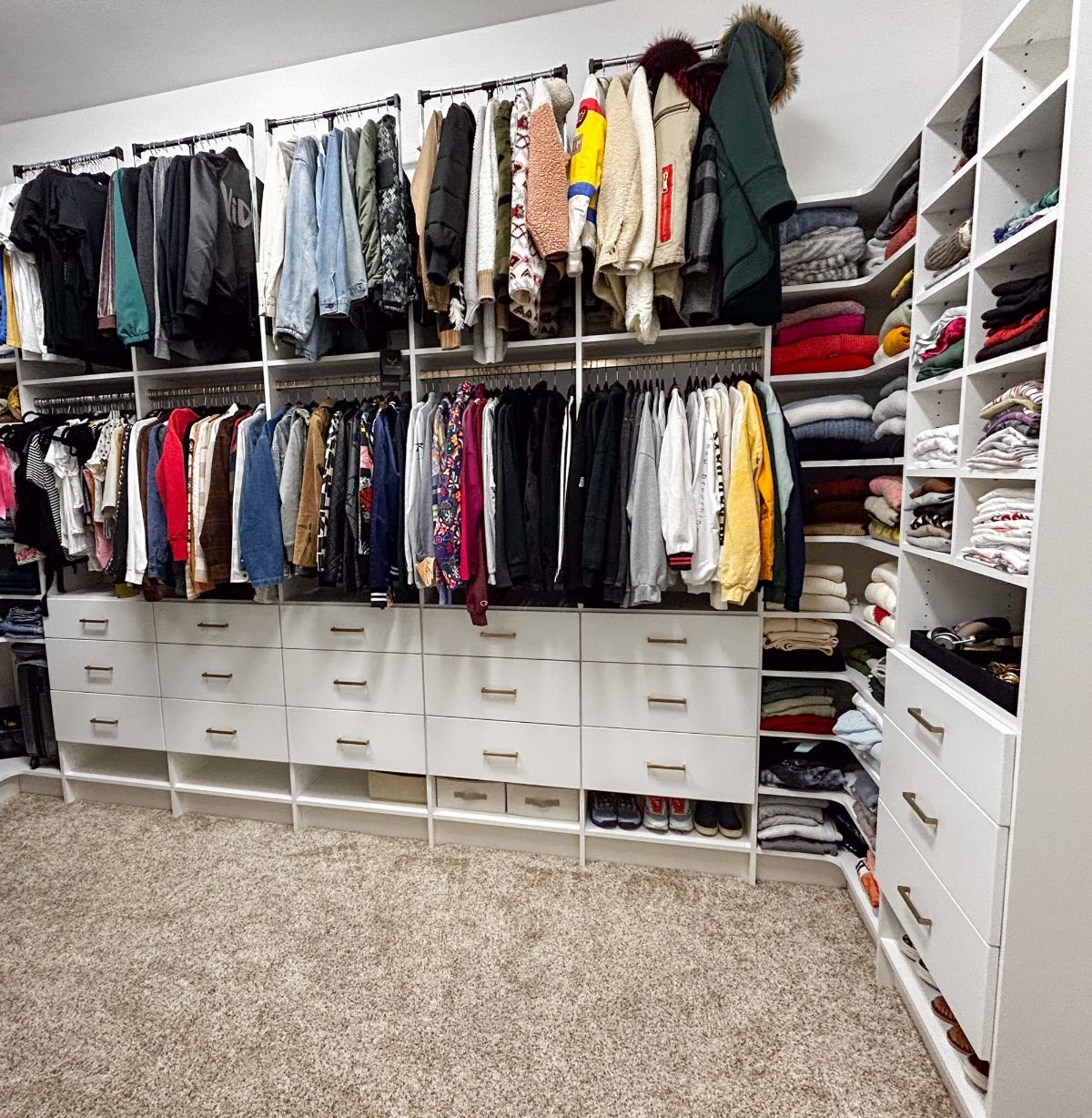 A walk in closet filled with lots of clothes and drawers.