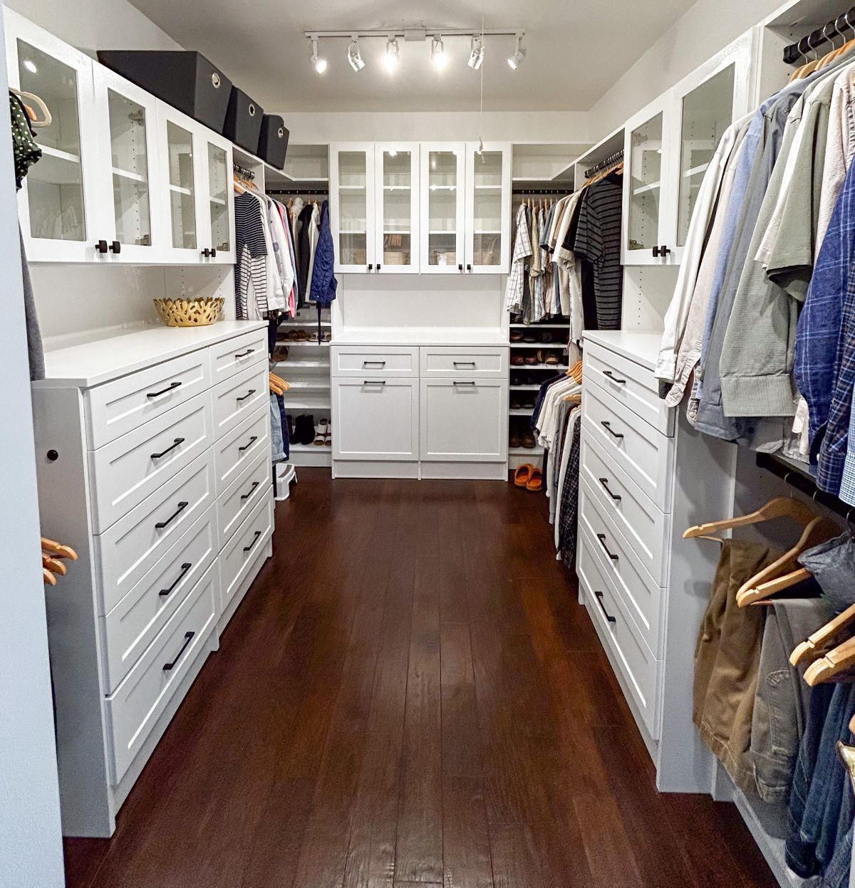 A walk in closet with lots of clothes and drawers