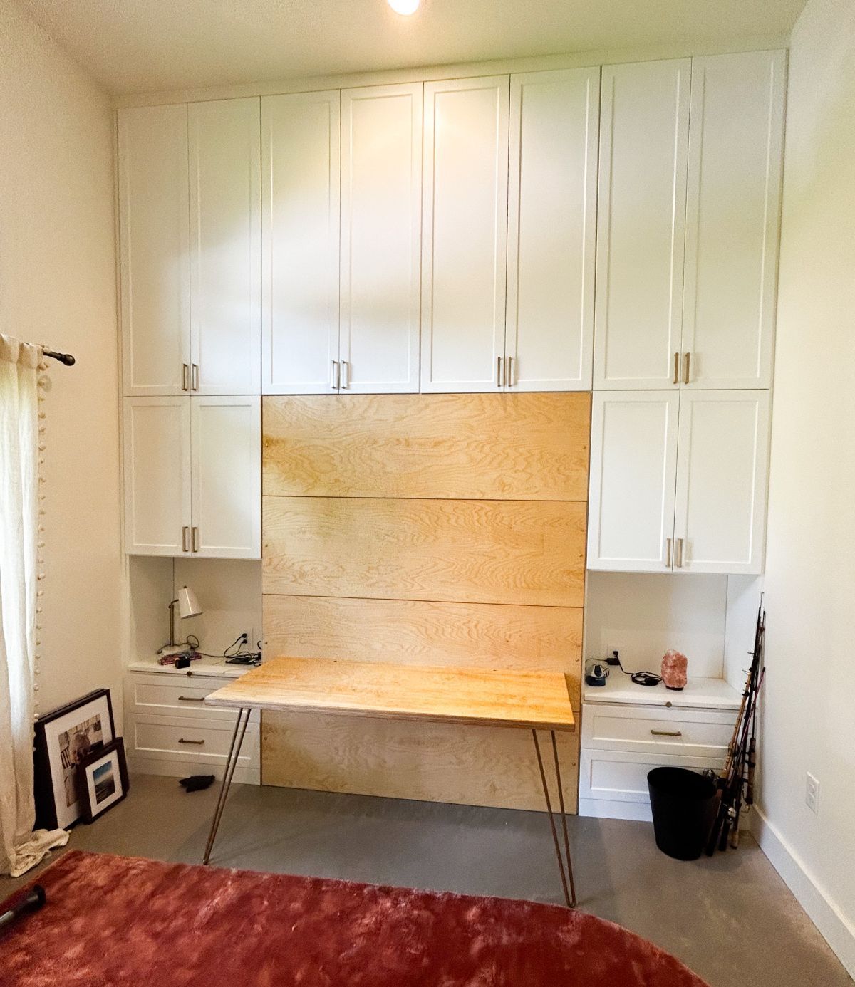 A bedroom with white cabinets and a wooden desk