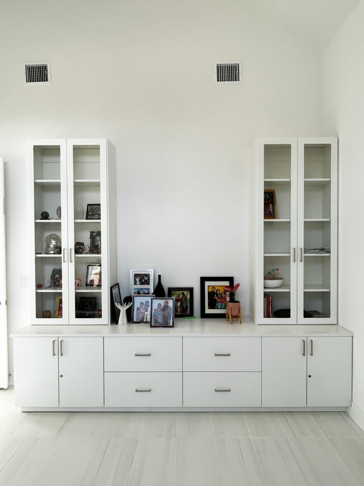 A living room with white cabinets , drawers , and glass doors.