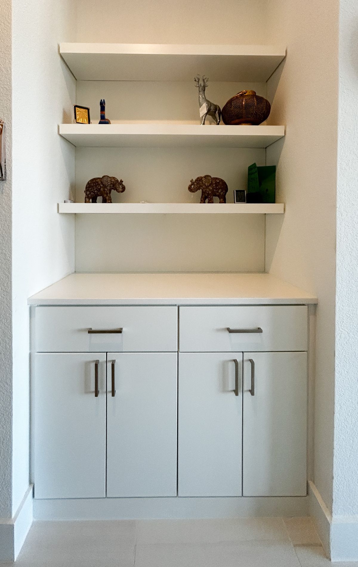 A corner of a room with white cabinets and shelves