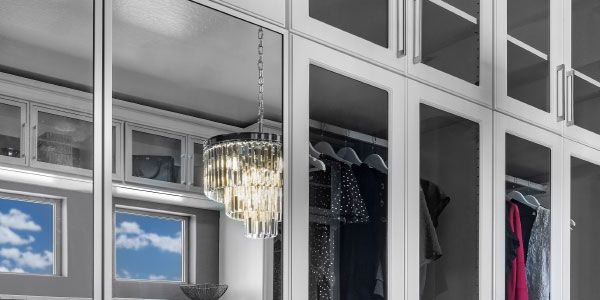 a walk in closet with lots of clothes and a chandelier hanging from the ceiling .