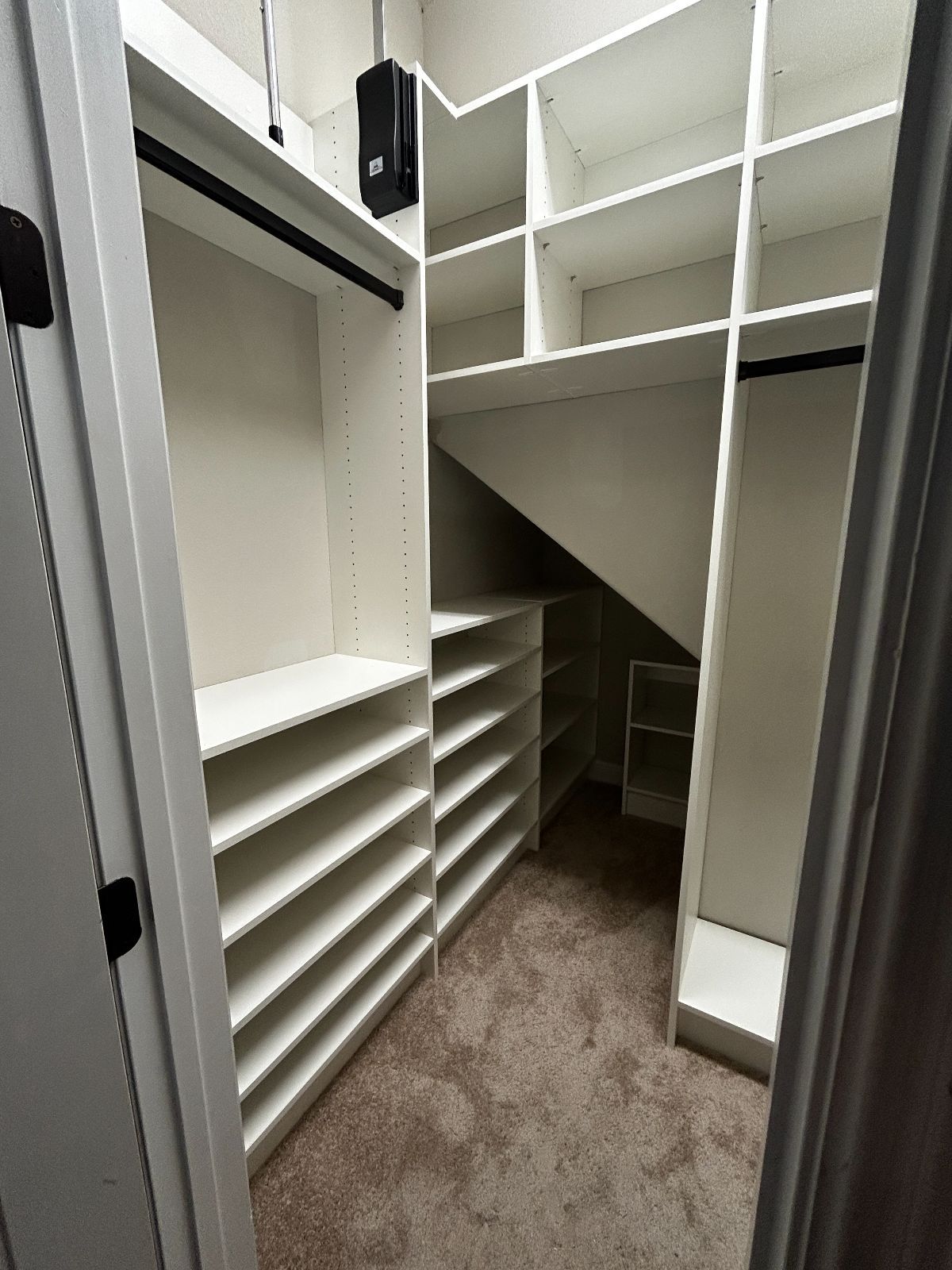 White, organized walk-in closet with shelves and hanging rods. Carpeted floor.