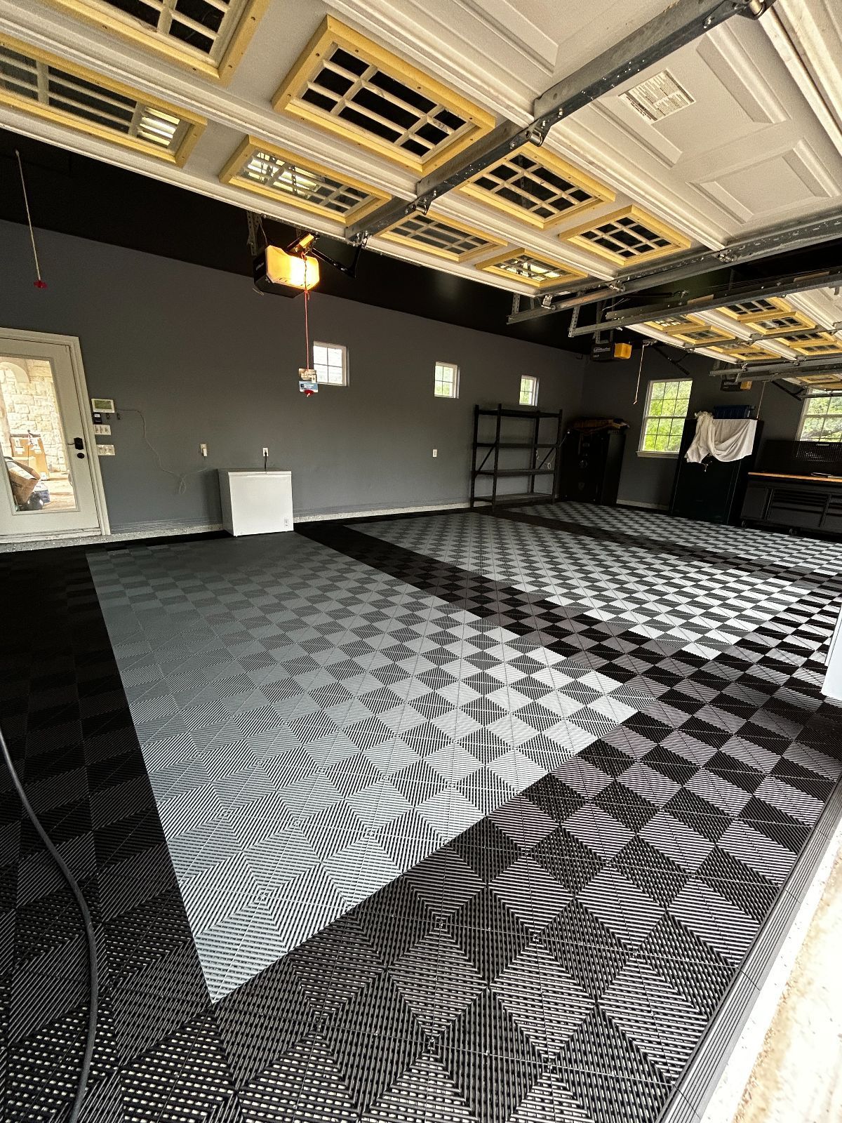 Garage interior with checkered floor tiles, gray walls, and open garage door.