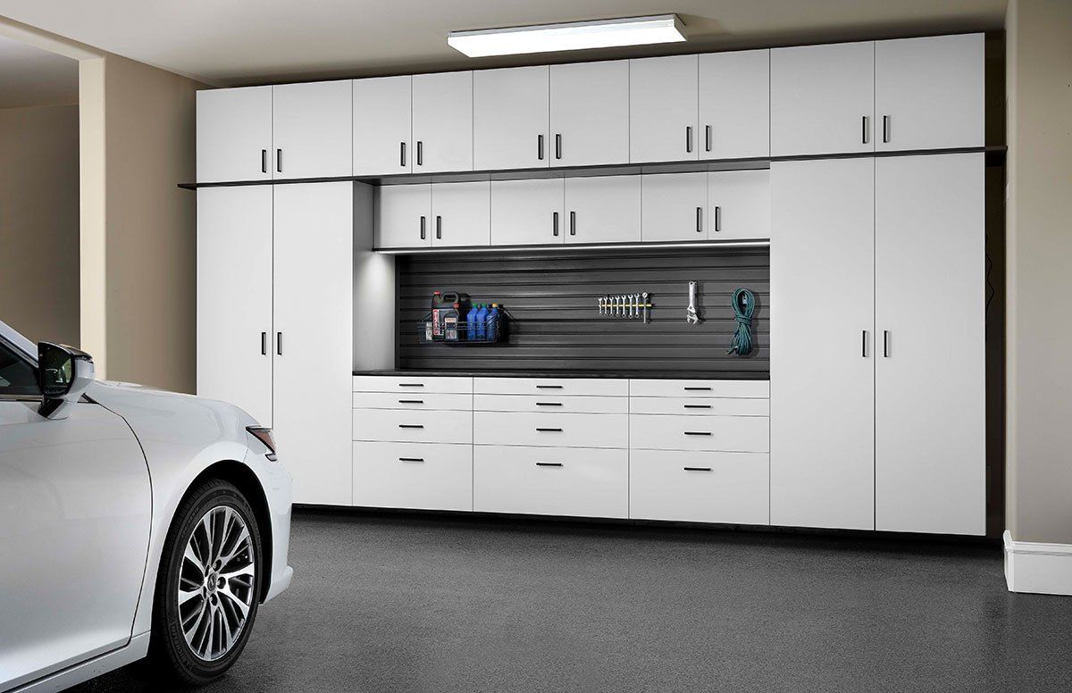 a car is parked in a garage with white cabinets .
