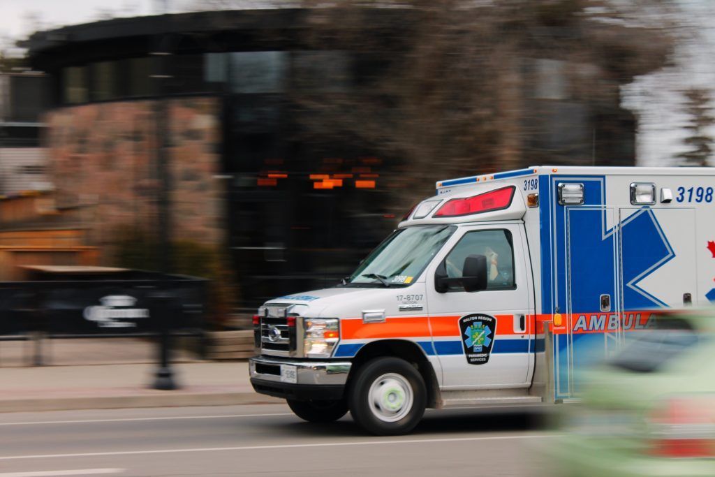 An ambulance is driving down the street in front of a building.