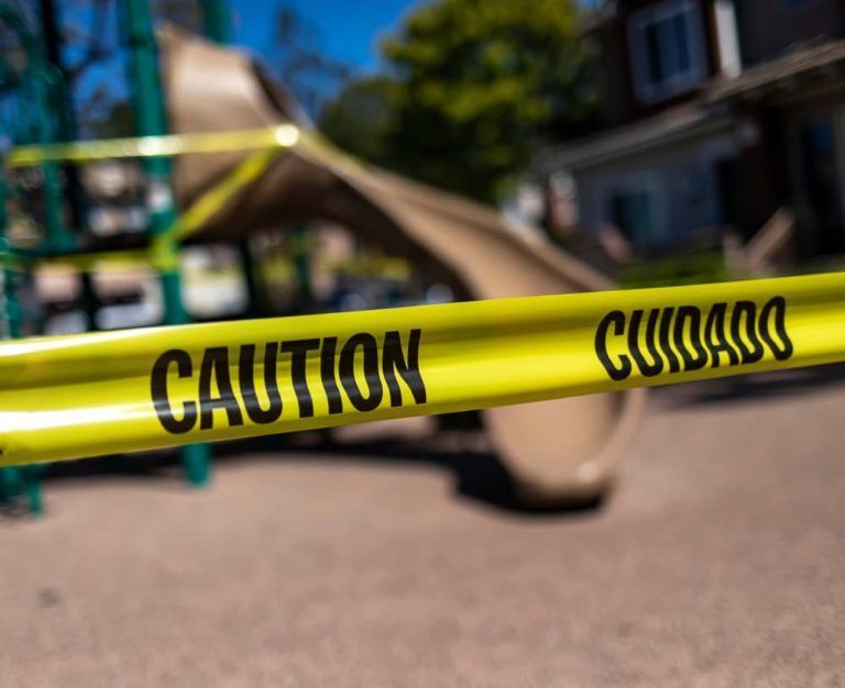 A close up of a yellow caution tape in front of a playground