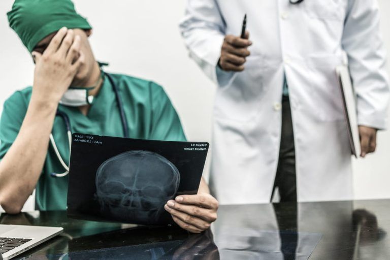 A doctor and a nurse are looking at an x-ray of a skull.