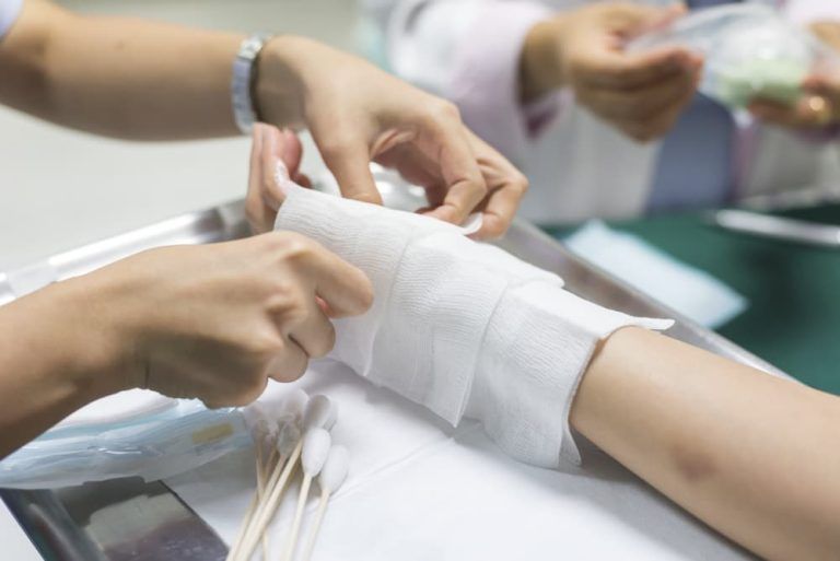 A person is getting a bandage on their wrist.