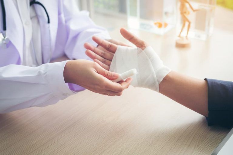 A doctor is bandaging a patient 's wrist.