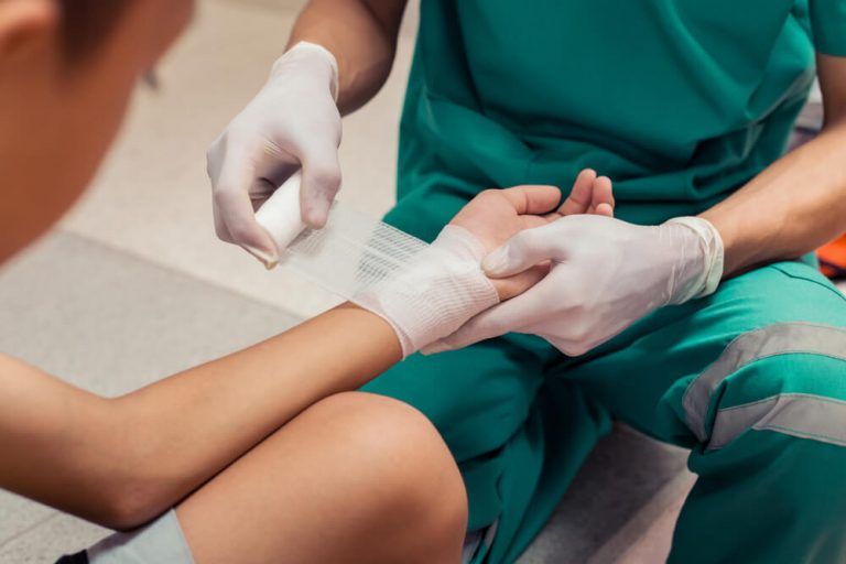 A doctor is bandaging a child 's wrist in a hospital.