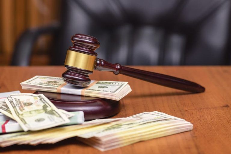 A judge 's gavel is sitting on top of a stack of money on a wooden table.
